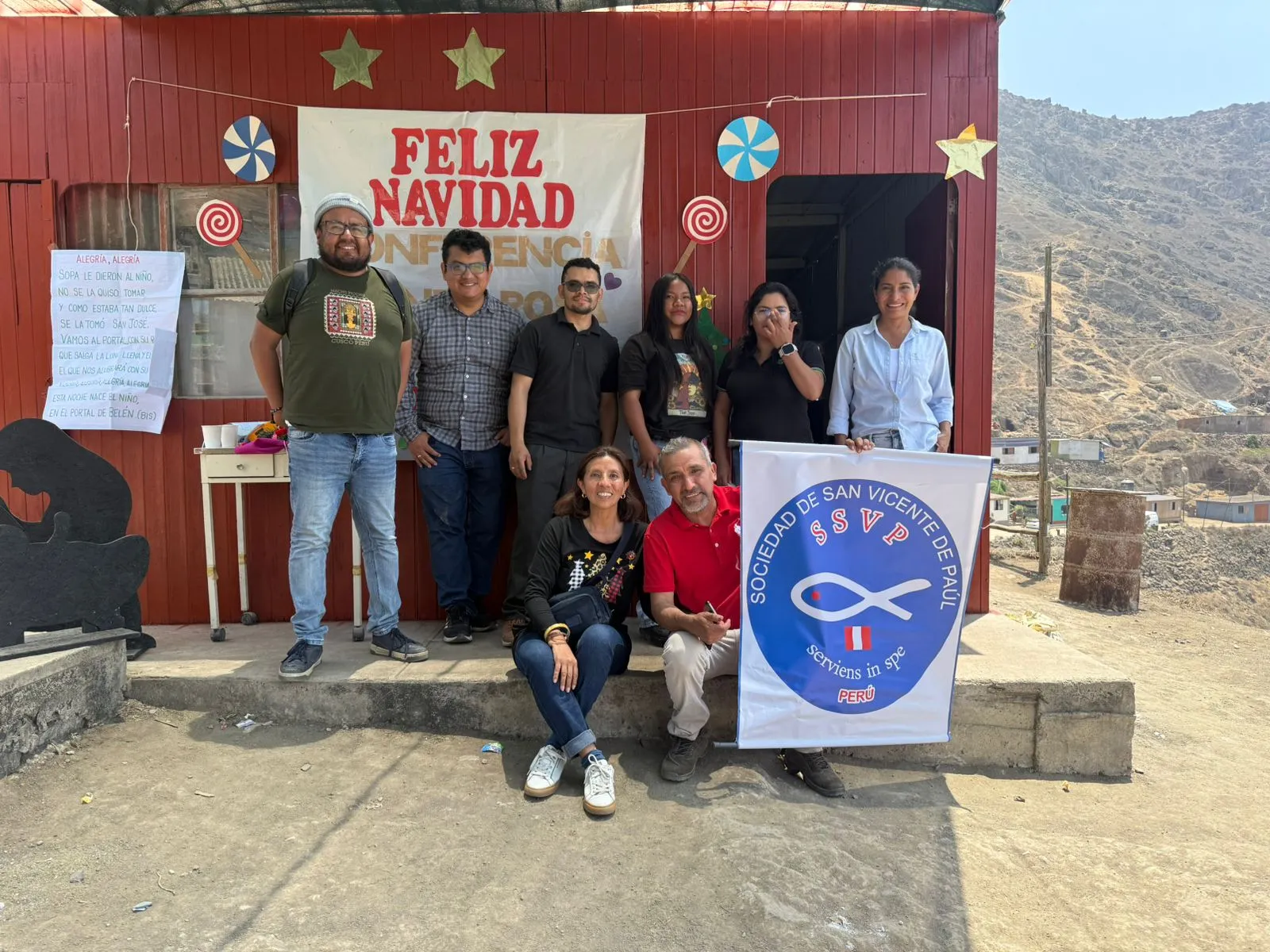 Equipo de la Conferencia Santa Rosa de Lima con el banner de la Sociedad de San Vicente de Paúl, en una chocolatada navideña
